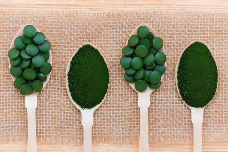 healthy lifestyle, superfood, seaweed, spirulina and chlorella pills and powder in wooden spoons