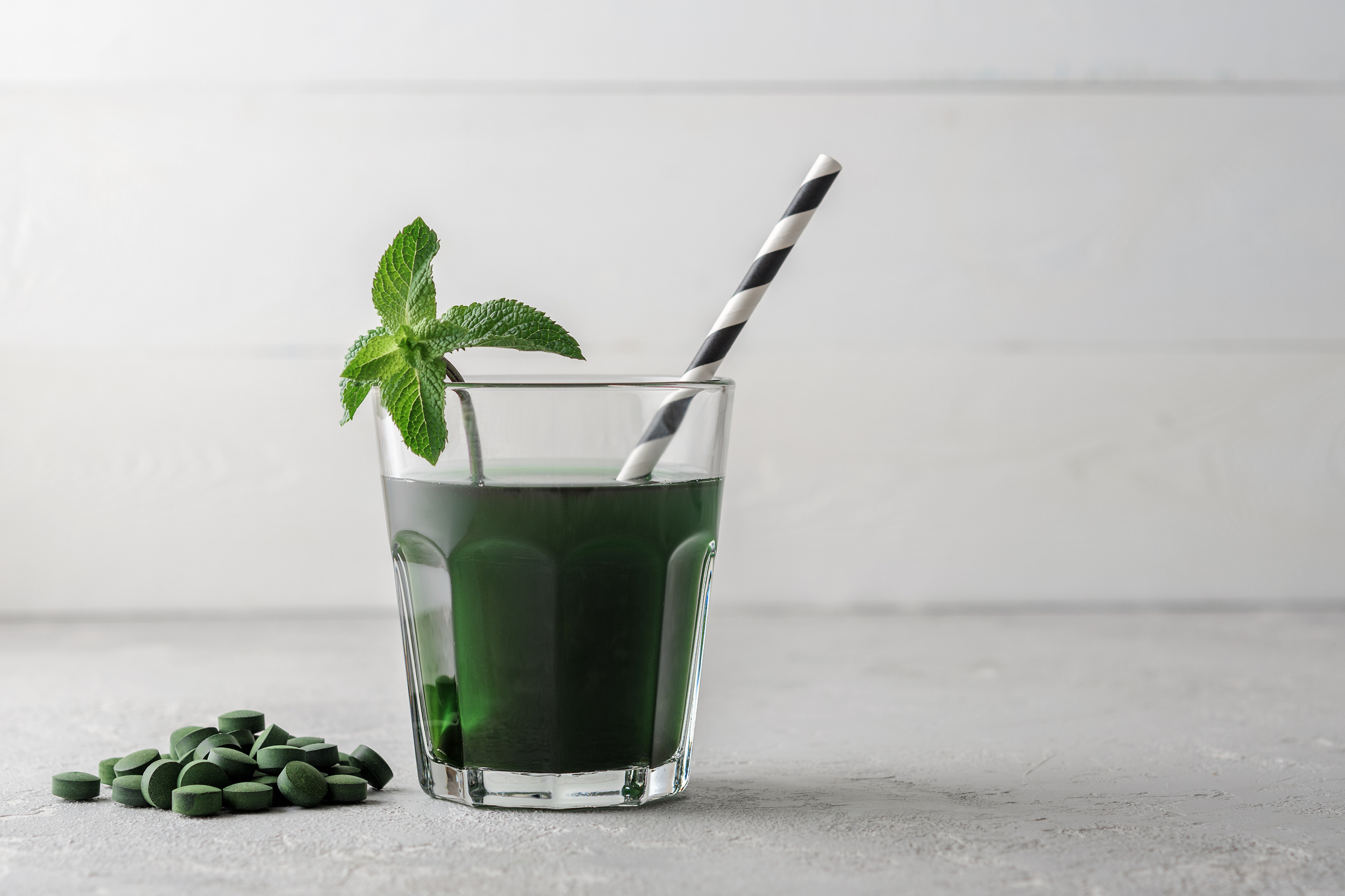 Refreshing chlorella cocktail with mint on grey concrete. Glass of lemonade with chlorella or spirulina. Detox.